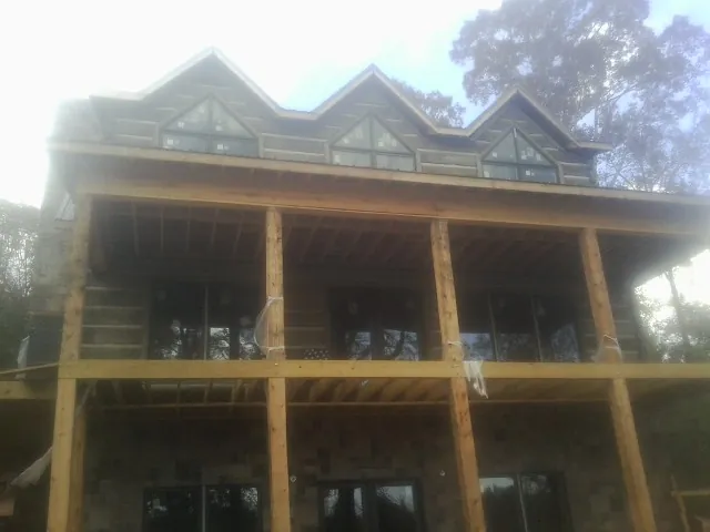 Dormers and porch framing on a large log home under construction — Roof Coating work by our crew in Madbury