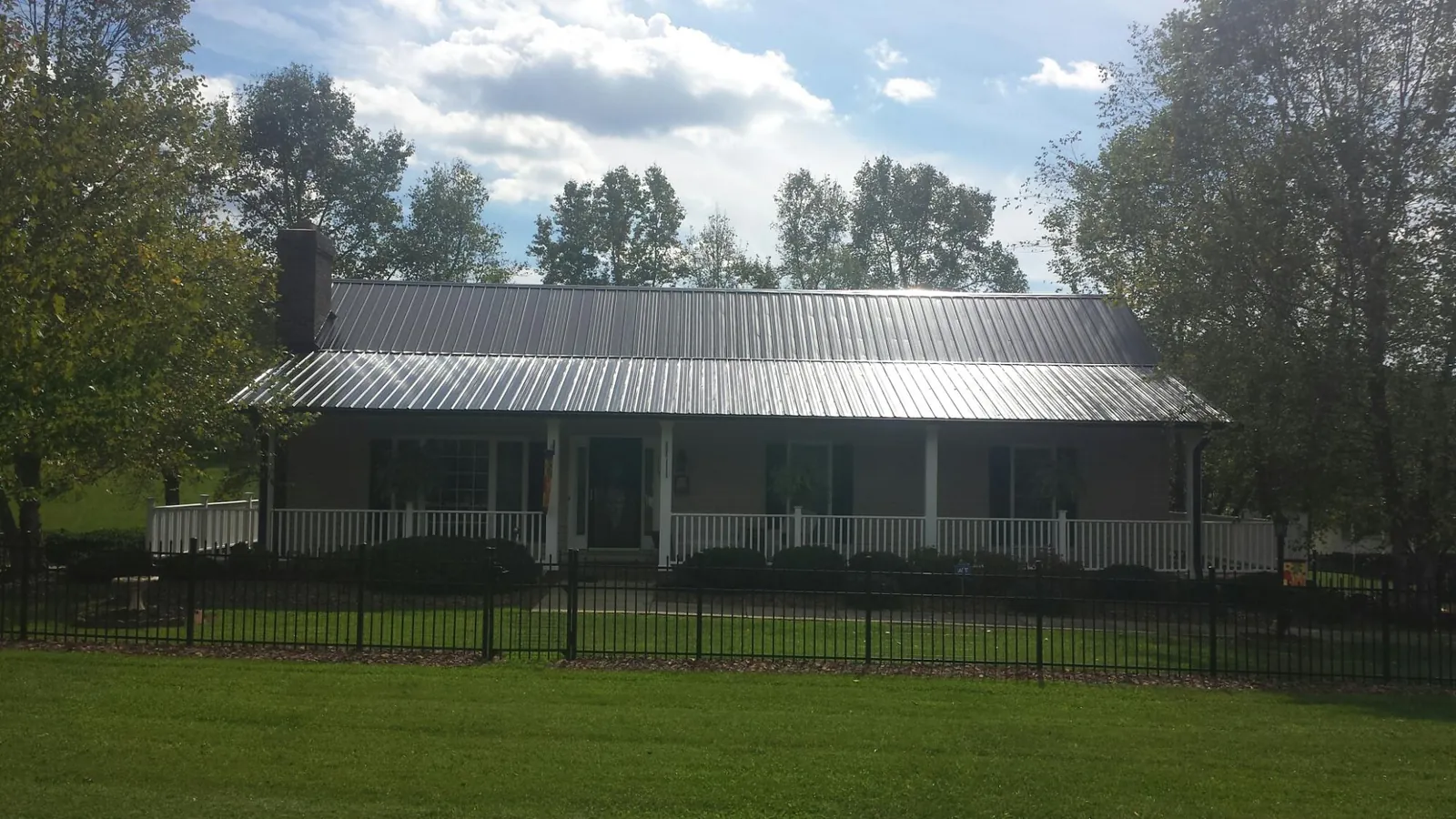Gray metal roof on a brick ranch with a full width front porch — Gutter Guard Installation work by our crew in Madbury