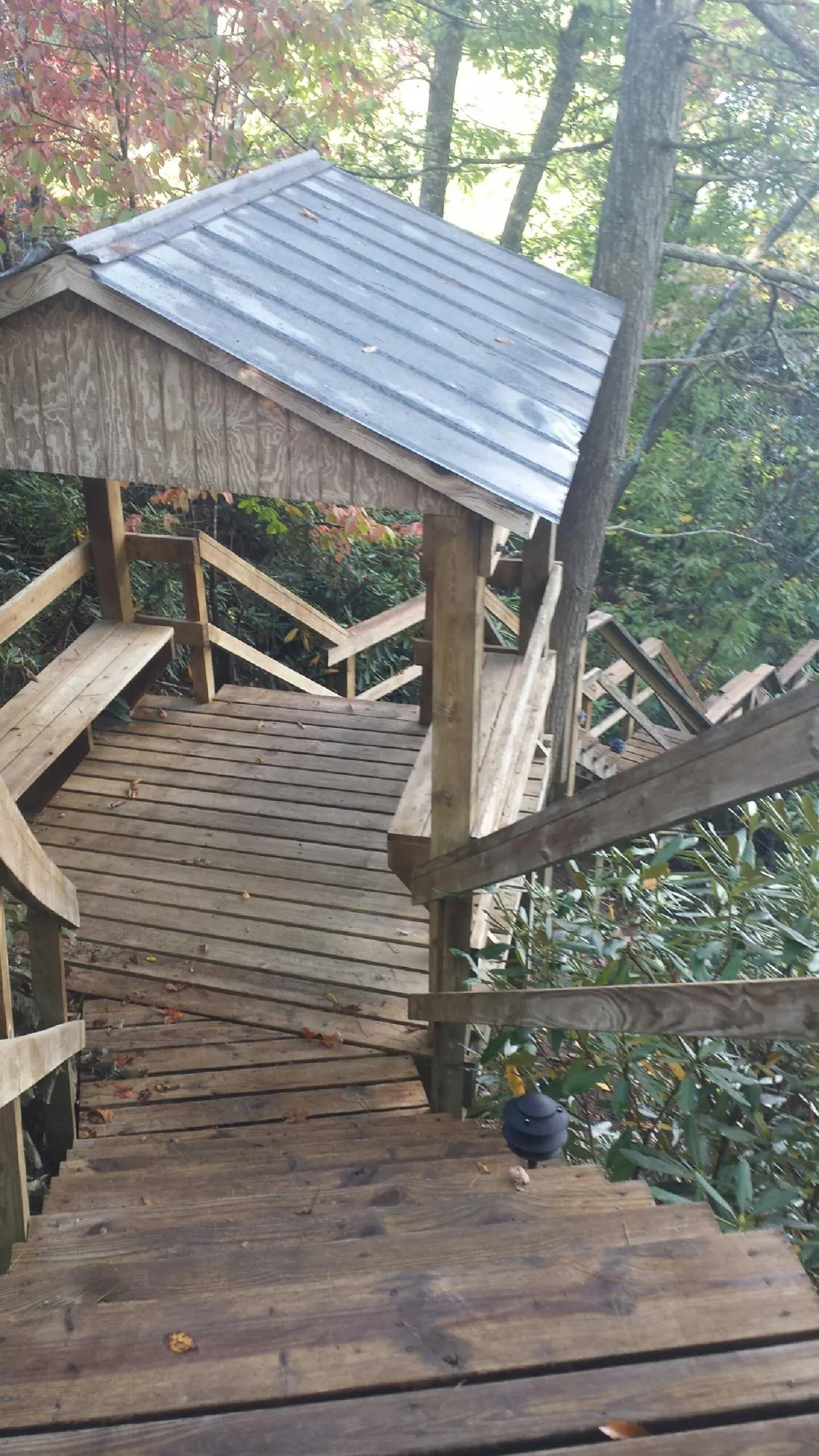 Metal roofed shelter over wooden steps on a wooded walkway — Skylight Repair & Installation work by our crew in Madbury