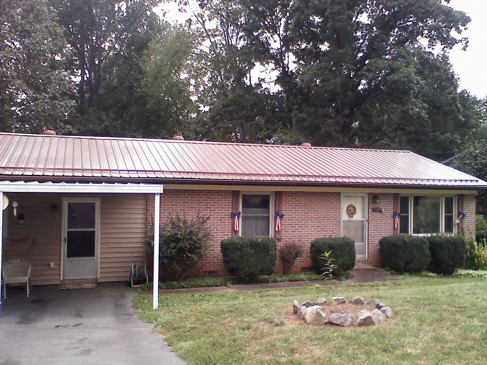 Bronze metal roof and carport on a brick ranch home — Roof Repair work by our crew in Madbury