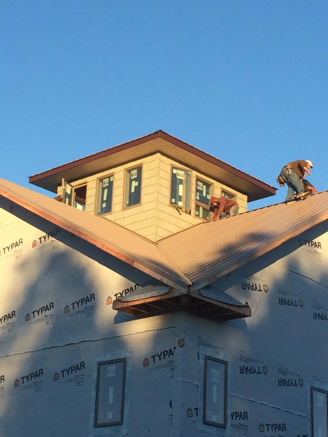 Roofers working around a rooftop cupola on a new metal roof at sunset — Roof Waterproofing in Madbury by Roofing Brothers